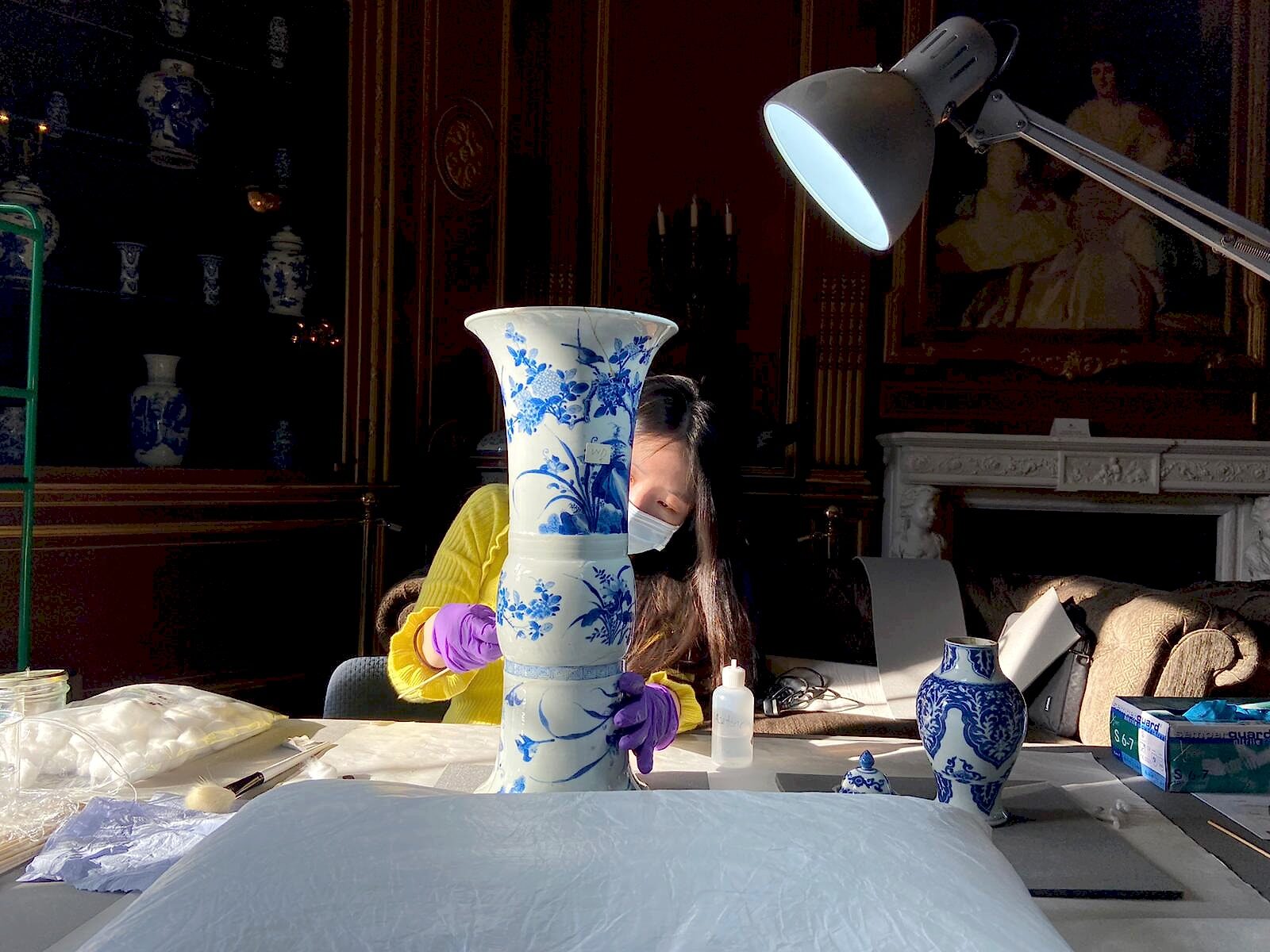 Sujin Jung examining a blue-and-white porcelain vase during on-site service.